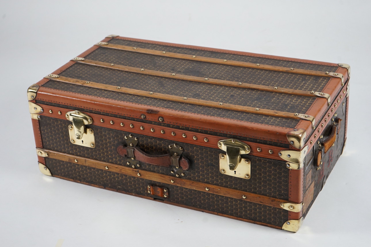 A vintage Moynat cabin trunk, with brass mounts, wooden slats and tan leather bound M motif canvas, the interior with quilted lining inside the lid and two canvas trays, 90cm wide, 53cm deep, 33cm high. Condition - very